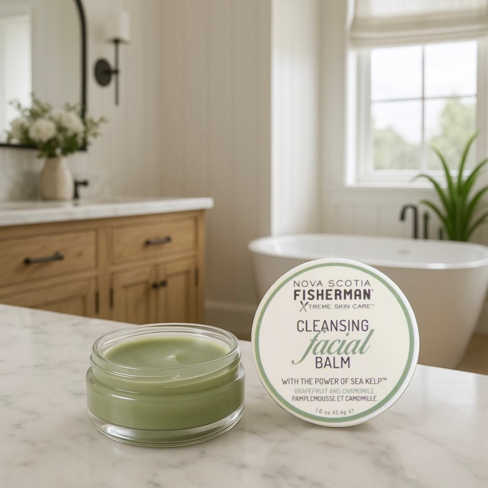 A container of Nova Scotia Fisherman Cleansing Facial Balm placed on a rock with daisies around it, and a scenic coastal background